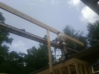 Carpenter setting a ridge beam over a new addition frame — Ice Dam Removal by Roofing Brothers in Coaldale