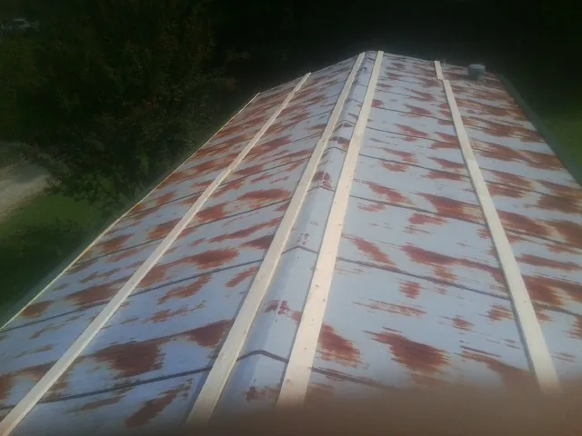 Rusted metal roof panels with new wood purlins before replacement — Storm Damage Roof Repair in Coaldale by Roofing Brothers