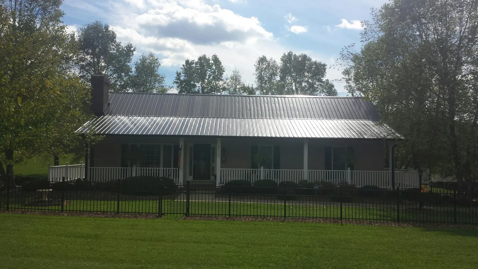 Gray metal roof on a brick ranch with a full width front porch — Gutter Guard Installation work by our crew in Coaldale