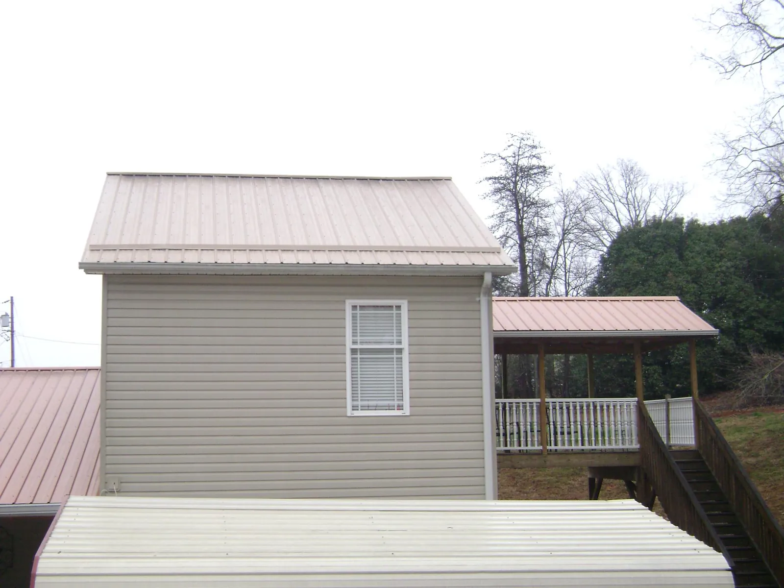 Tan metal roofs on a two story addition and attached porch, from a Roof Replacement job in Coaldale