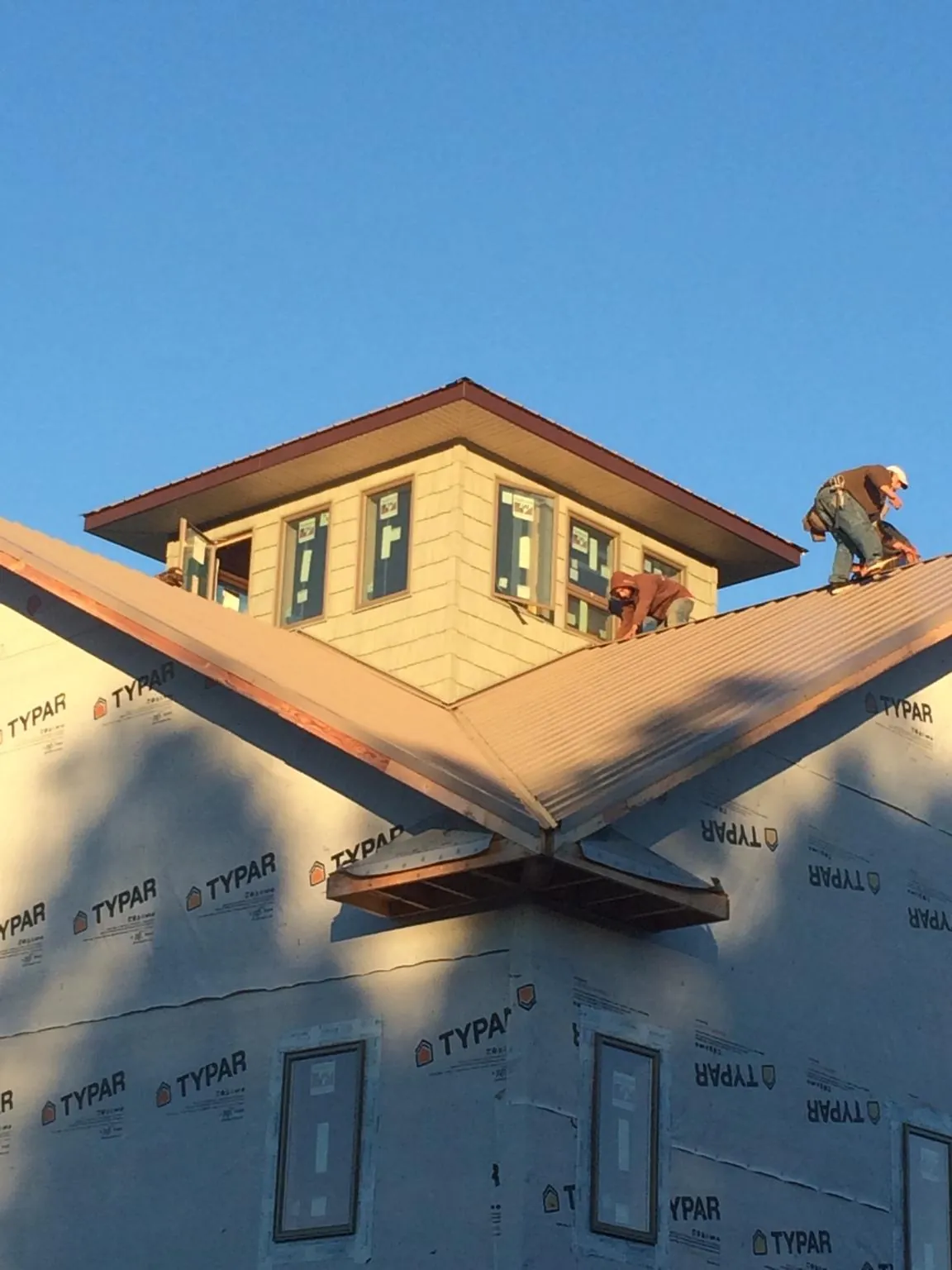 Roofers working around a rooftop cupola on a new metal roof at sunset — Roof Waterproofing in Coaldale by Roofing Brothers